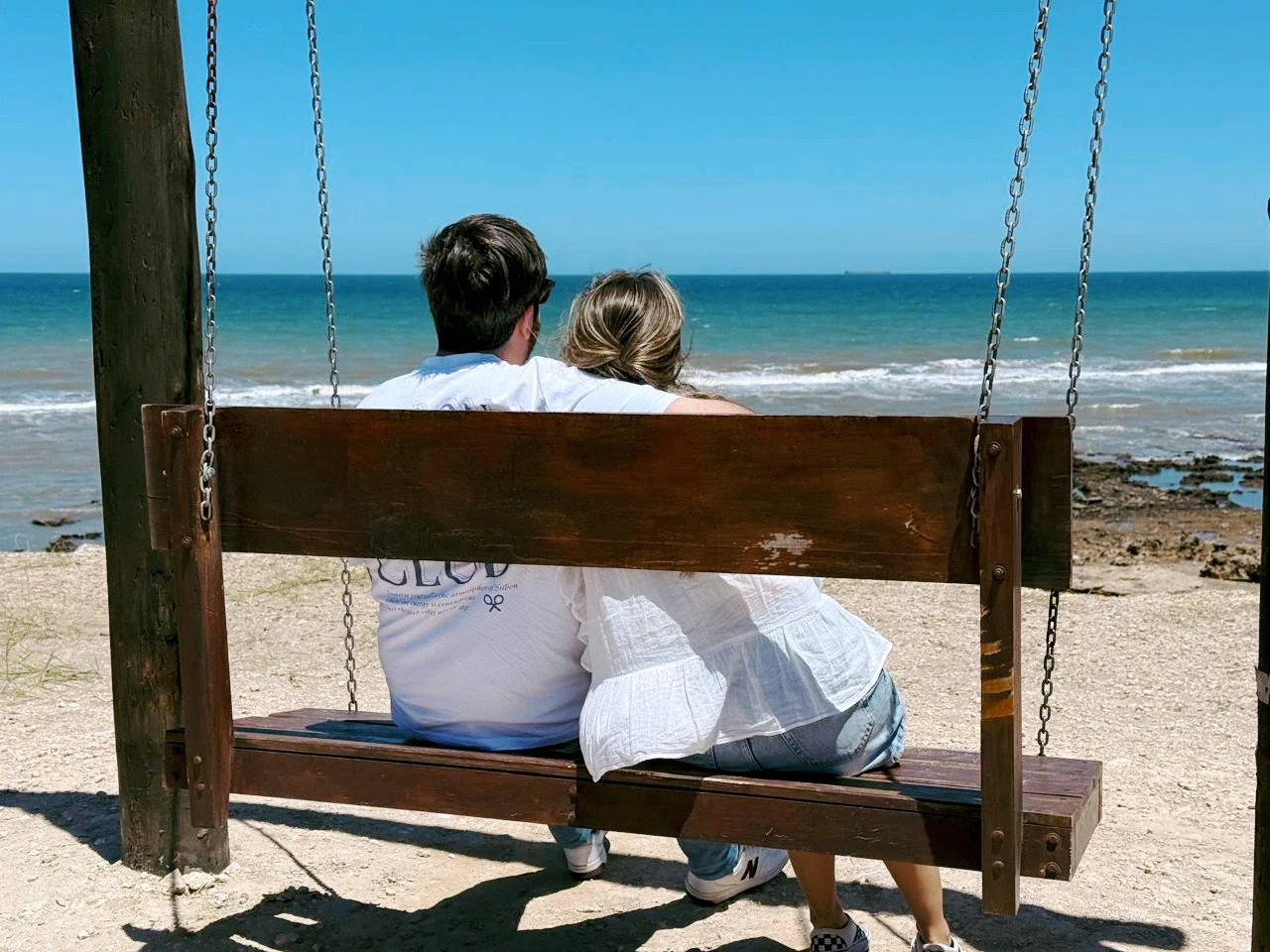 Sofía y Alberto juntos en un columpio frente al mar